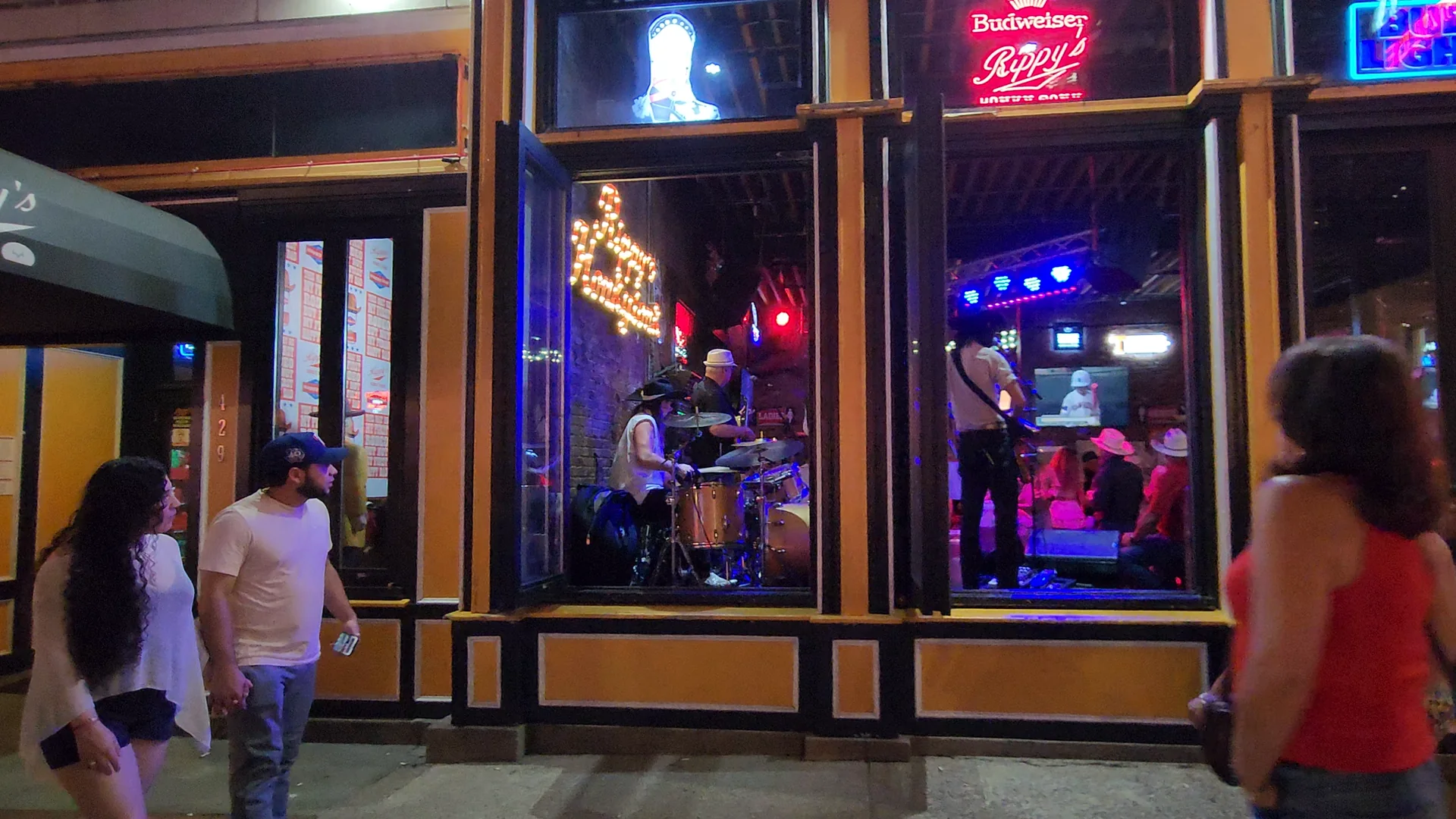 Live music is visible through an open Lower Broadway venue from the sidewalk.